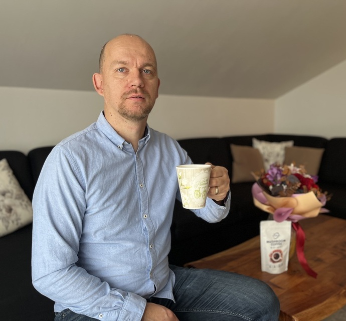 Osoba uživa u šalici kave s adaptogenima u ugodnom kućnom okruženju, uz proizvod Vitela na stolu.